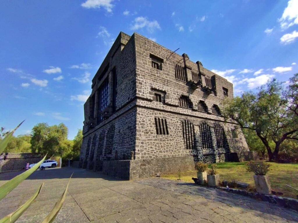 Vista exterior del Museo Anahuacalli, edificio de piedra volcánica con cielo azul y árboles alrededor.