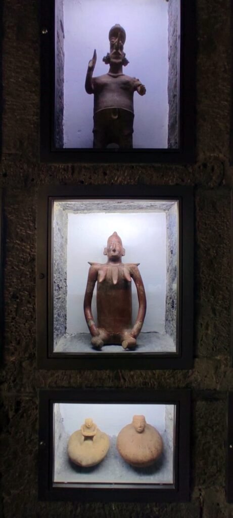 Nichos verticales con figuras y piezas de cerámica exhibidas en el muro de piedra del Museo Anahuacalli.