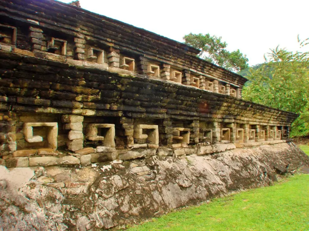 Fachada lateral de edificio ceremonial en El Tajín con repetición de nichos y muros de piedra.