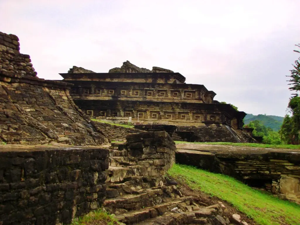 Vista profunda de plataformas y escalinatas en El Tajín, rodeadas de vegetación tropical.