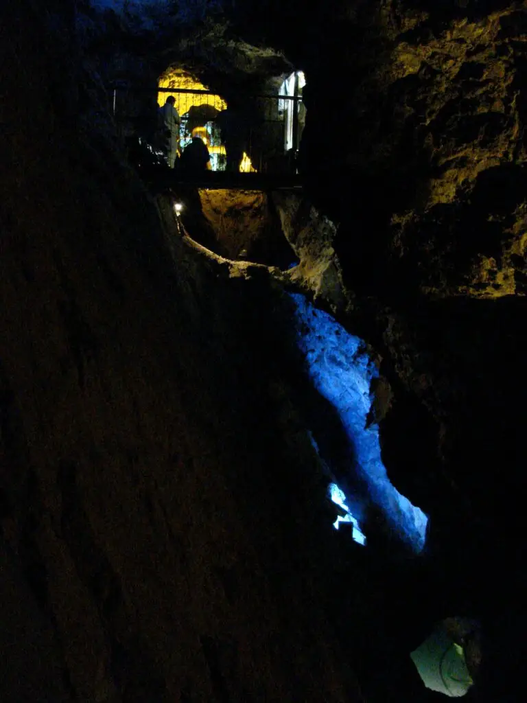 Pasarela suspendida dentro de la Mina del Edén con visitantes observando formaciones rocosas iluminadas.