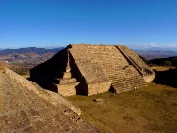 Estructura piramidal de Monte Albán con escalinata central y plataformas ceremoniales de piedra.
