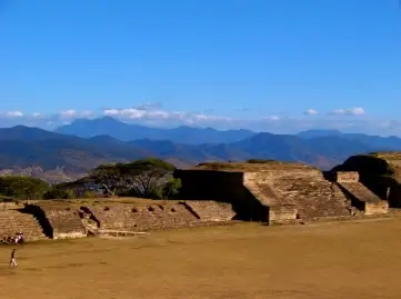 Conjunto arquitectónico de Monte Albán con plataformas y edificios de piedra frente al paisaje montañoso de Oaxaca.