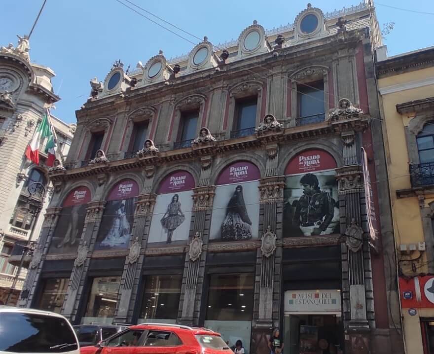 Fachada del Museo del Estanquillo en el Centro Histórico de CDMX, con anuncios y autos en la calle.