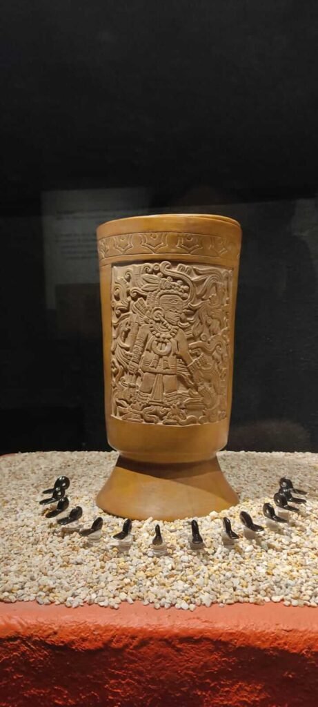 Vaso ceremonial con relieve tallado, exhibido sobre grava en el Museo del Templo Mayor.