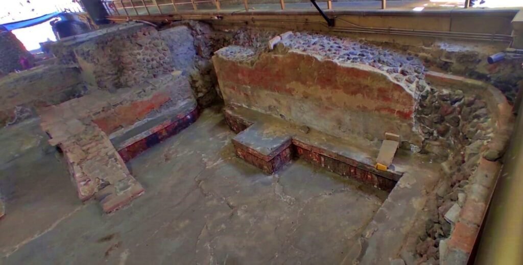 Detalle de friso tallado en piedra en la base de una estructura del Templo Mayor, con restos de pigmento rojo, CDMX.