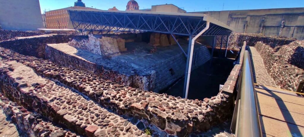 Estructuras escalonadas y área excavada con techumbre en el Templo Mayor, mostrando capas constructivas, CDMX.