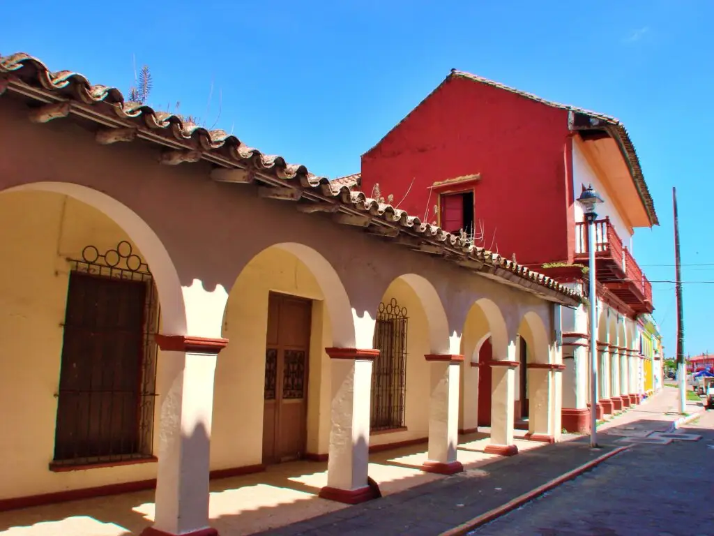 Calle tradicional de Tlacotalpan con arcos blancos en repetición, columnas alineadas y perspectiva profunda del centro histórico.de arcos blancos y rojos en perspectiva, arquitectura veracruzana bajo cielo despejado.