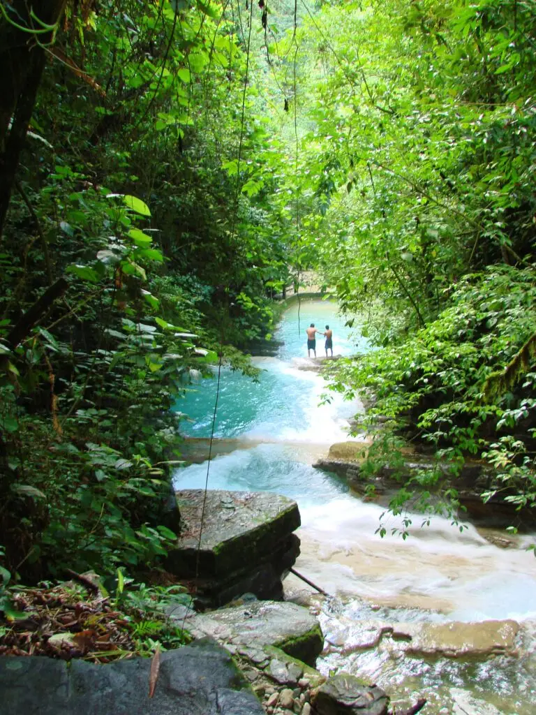 Río de agua turquesa rodeado de selva tropical con visitantes al fondo en el Jardín Surrealista de Xilitla.
